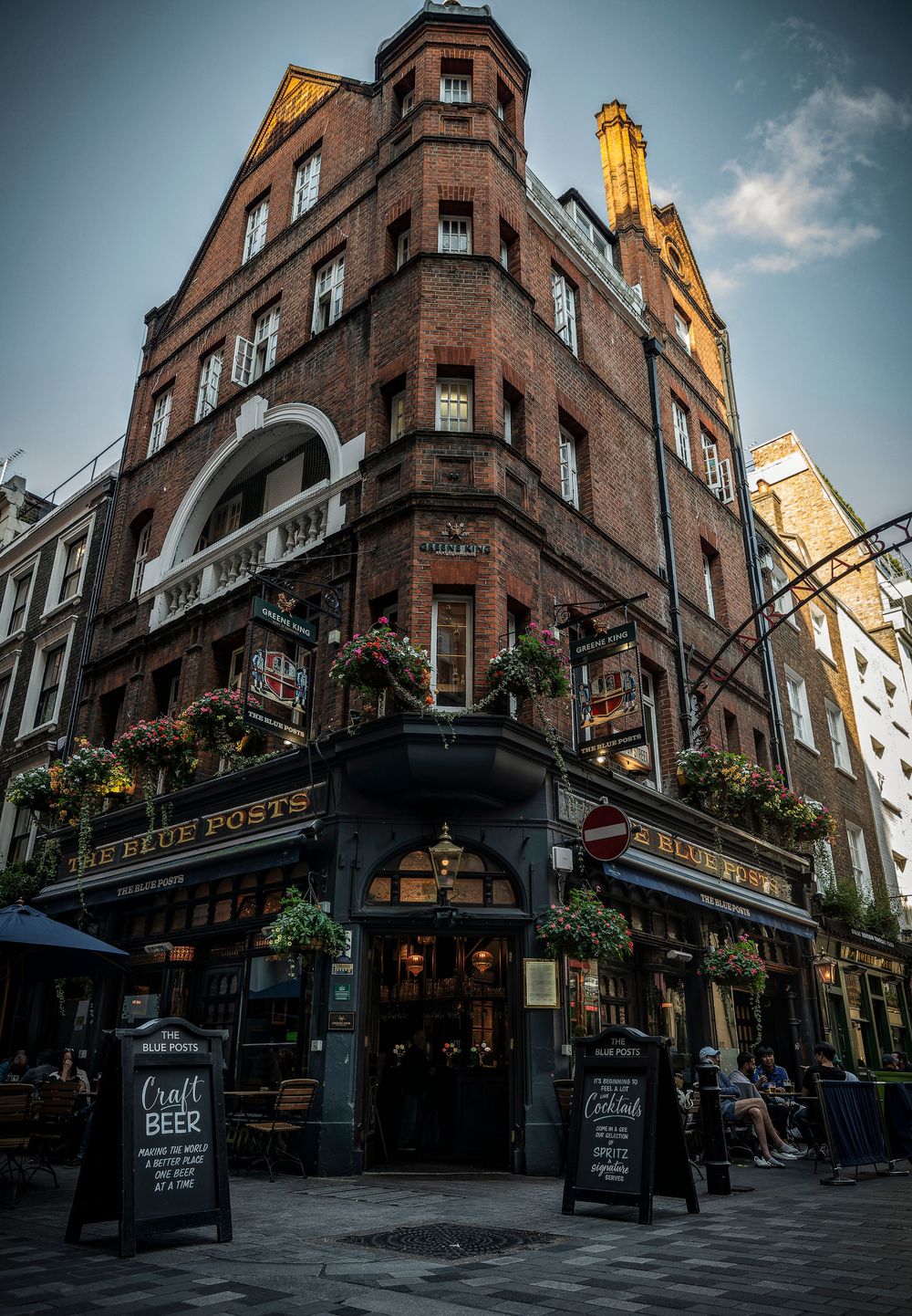 Historic brick buildings along a charming street in London's Carnaby district with pubs and shops under moody skies.
