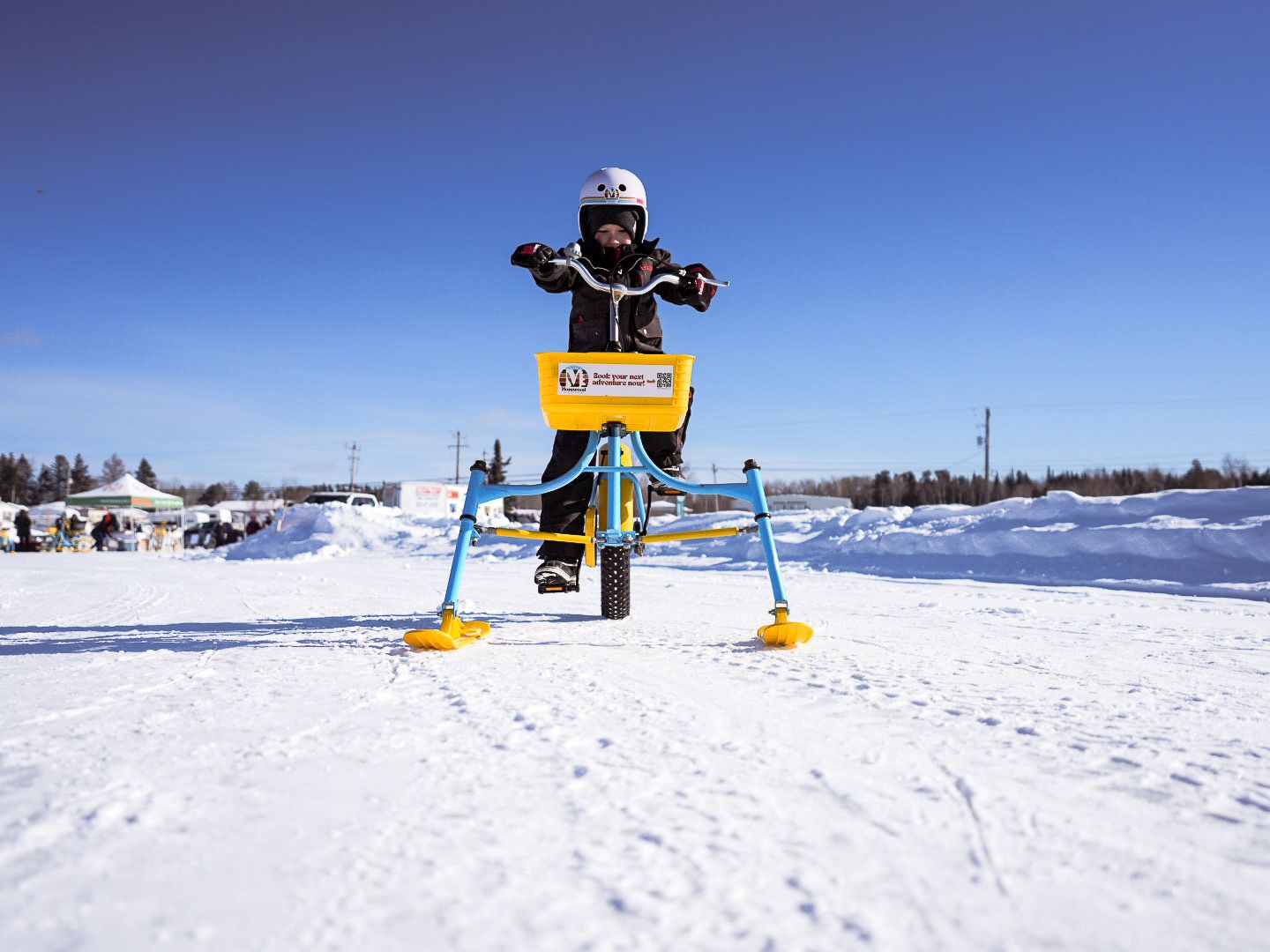 Wide angle view of a winter recreation area with snow bikes and equipment on frozen terrain.