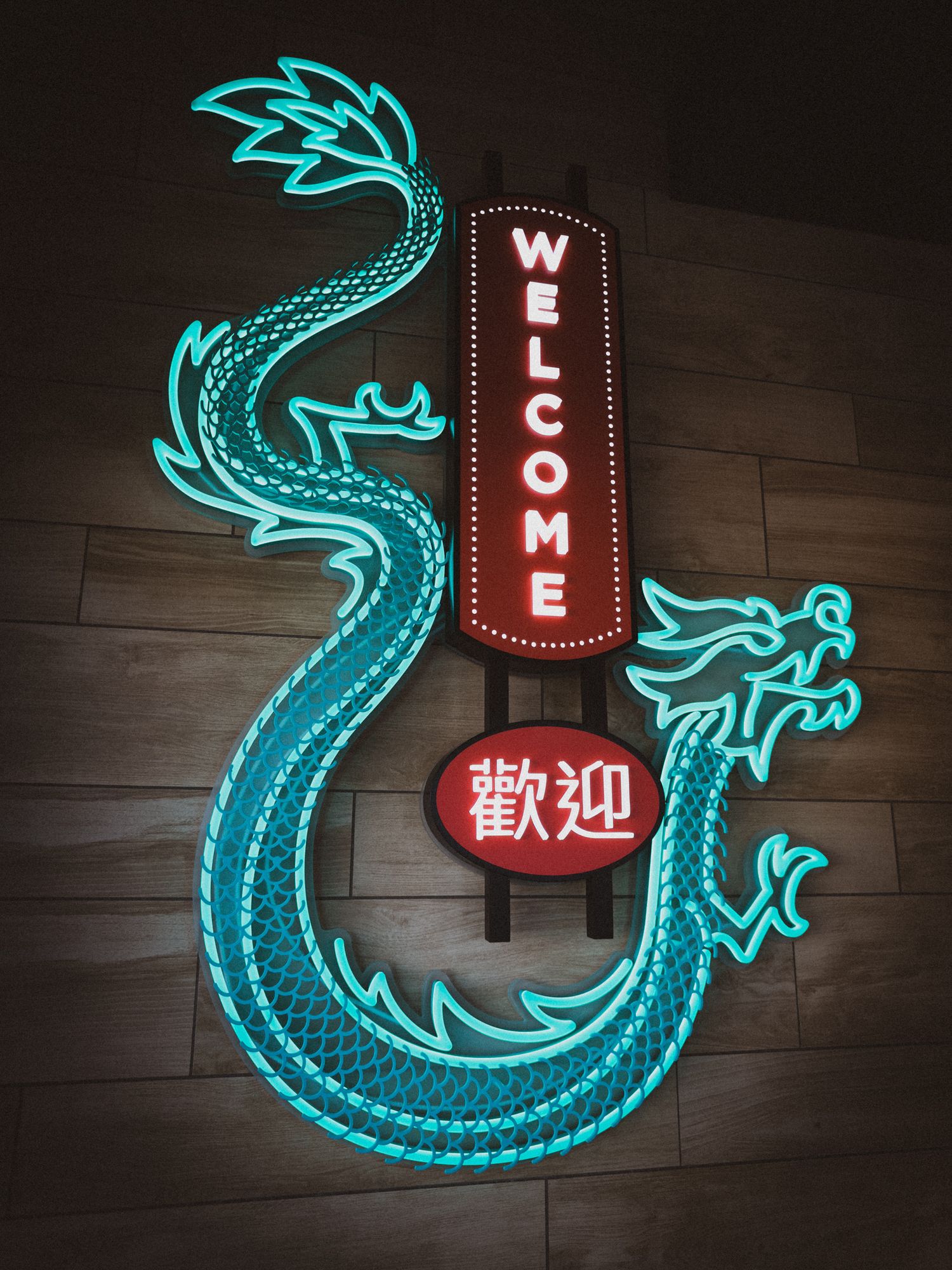 Neon blue dragon sign with Chinese characters and red accents mounted on dark wall.