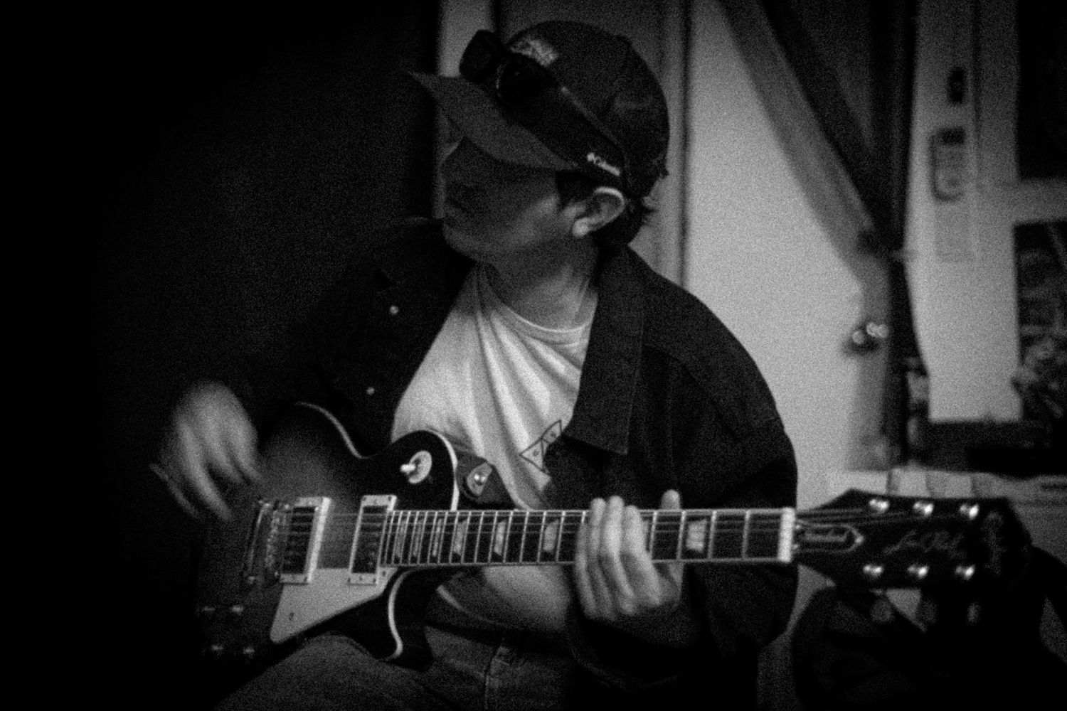 Black and white closeups of musicians playing guitars in a dimly lit setting.