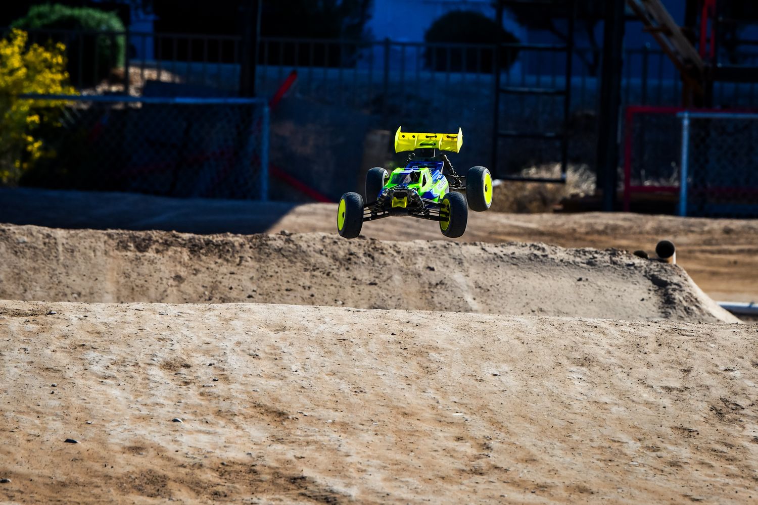 Remote controlled cars racing through dirt tracks in an outdoor setting.