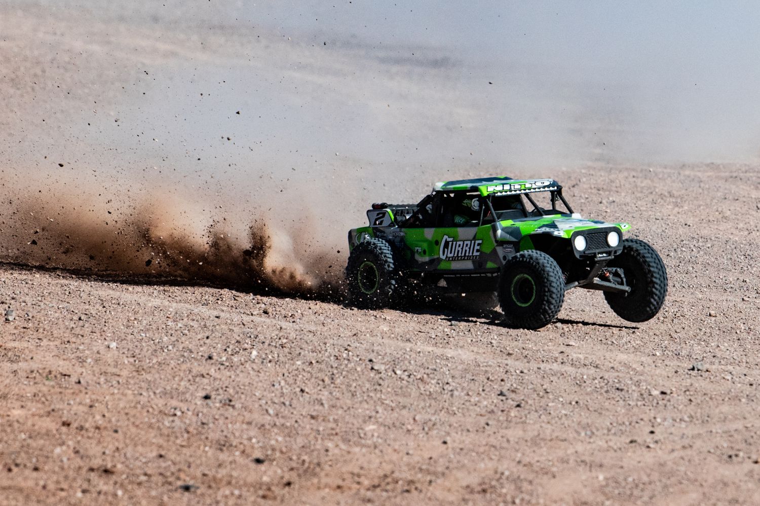 RC cars kicking up dust while racing through a desert course.