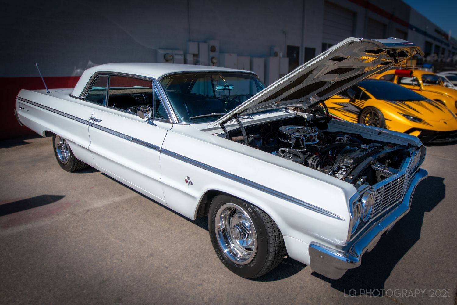 Row of classic white vintage cars displayed at an outdoor auto show.