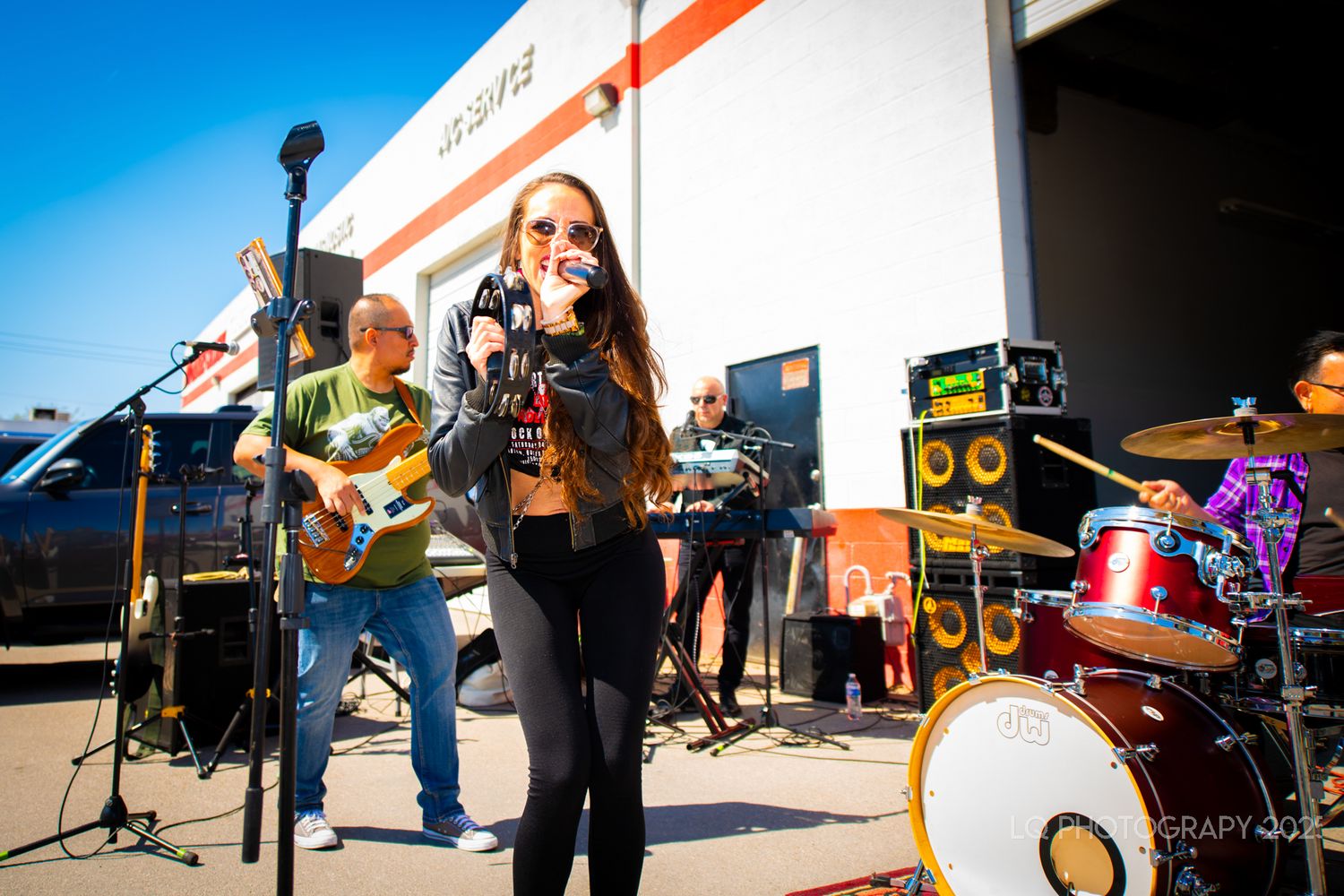 Band performing live music outdoors with singer and musicians on stage.