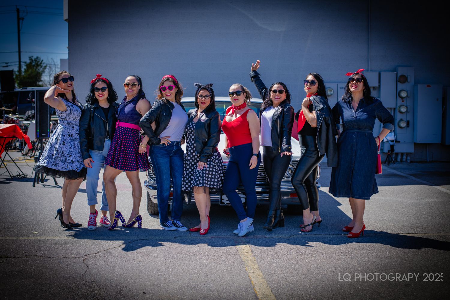 Group of people in retro outfits posing together at outdoor event.