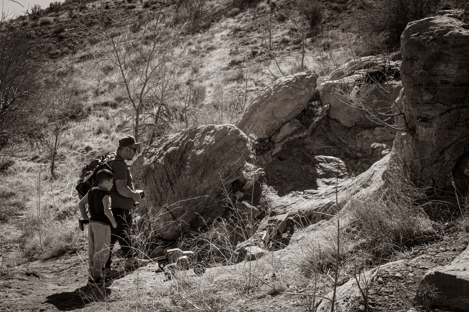 Hikers traversing rocky mountain terrain during an outdoor adventure in monochrome.