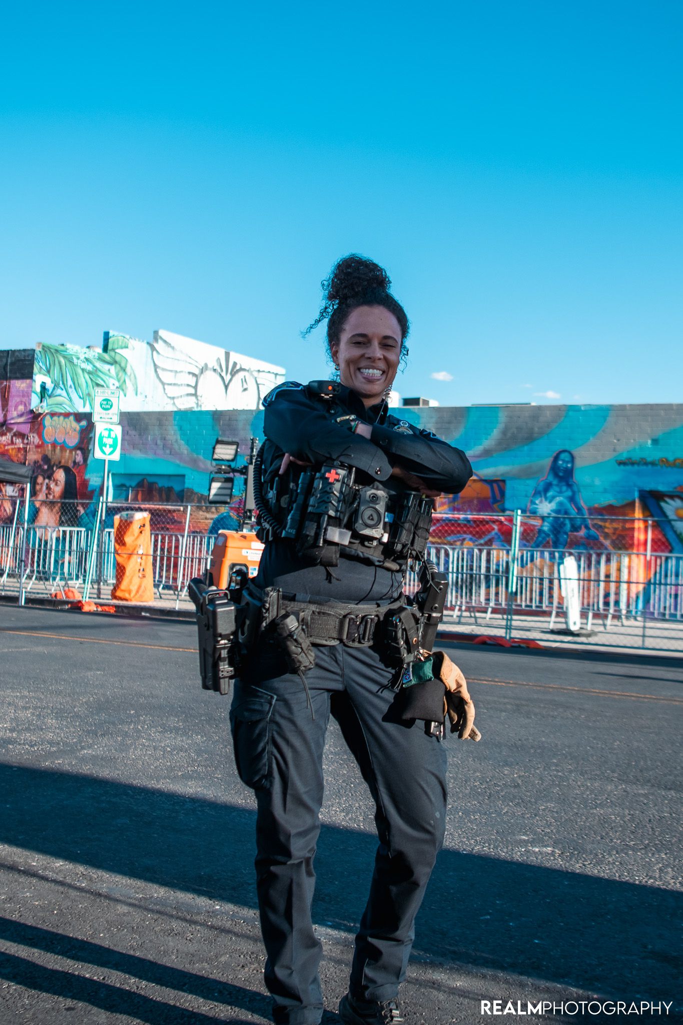 Camera operator with professional gear stands against colorful street art background.