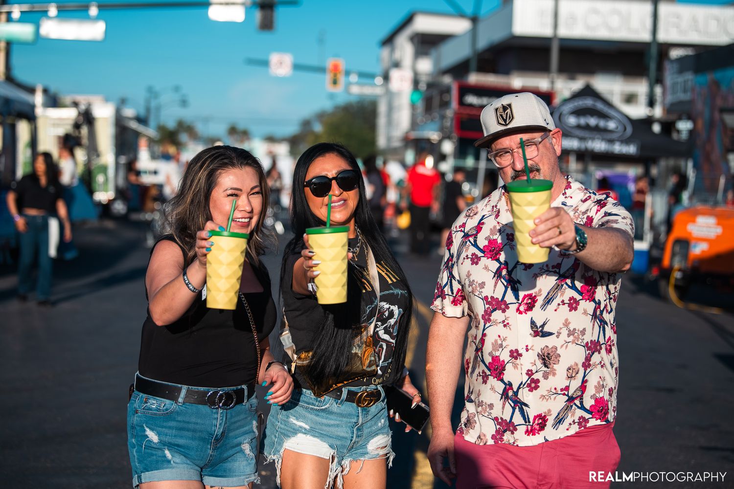 Festival attendees enjoying yellow beverages outdoors on a sunny day.