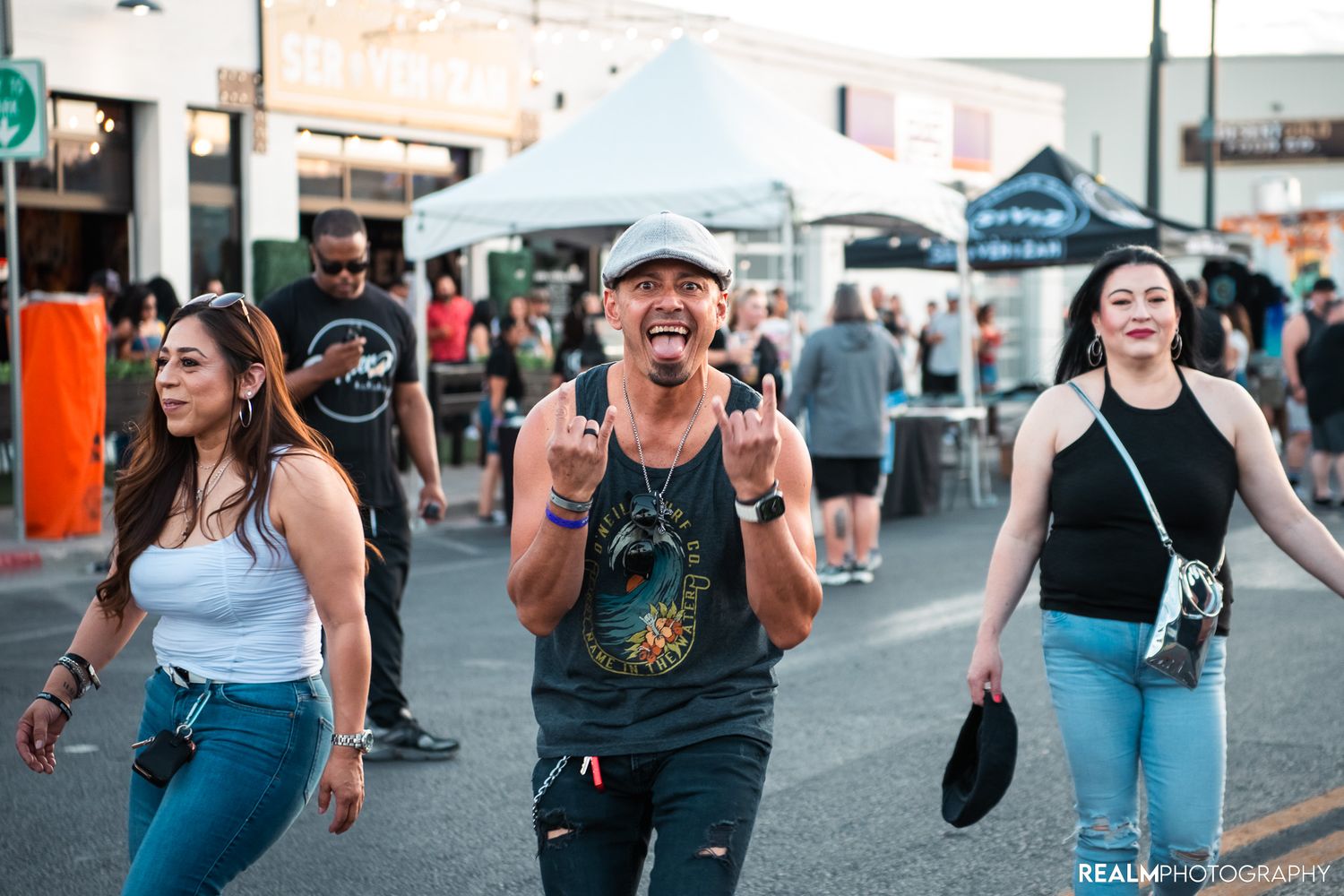 Crowd of people walking through outdoor festival on urban street.