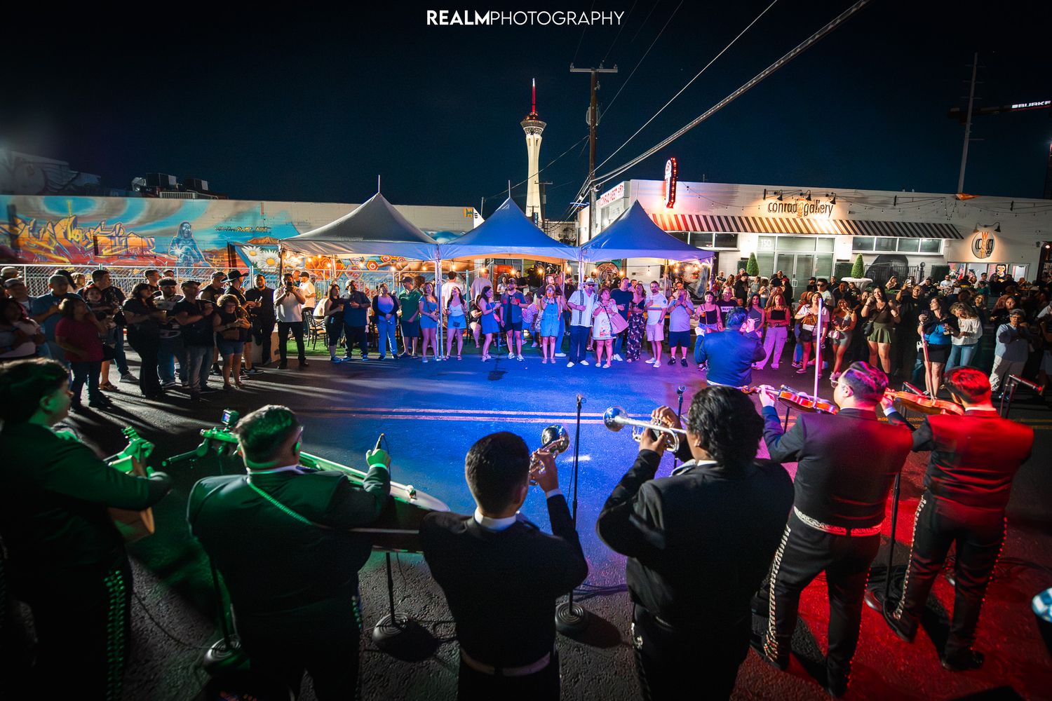 Crowd watching performance under colorful lights at outdoor nighttime event.