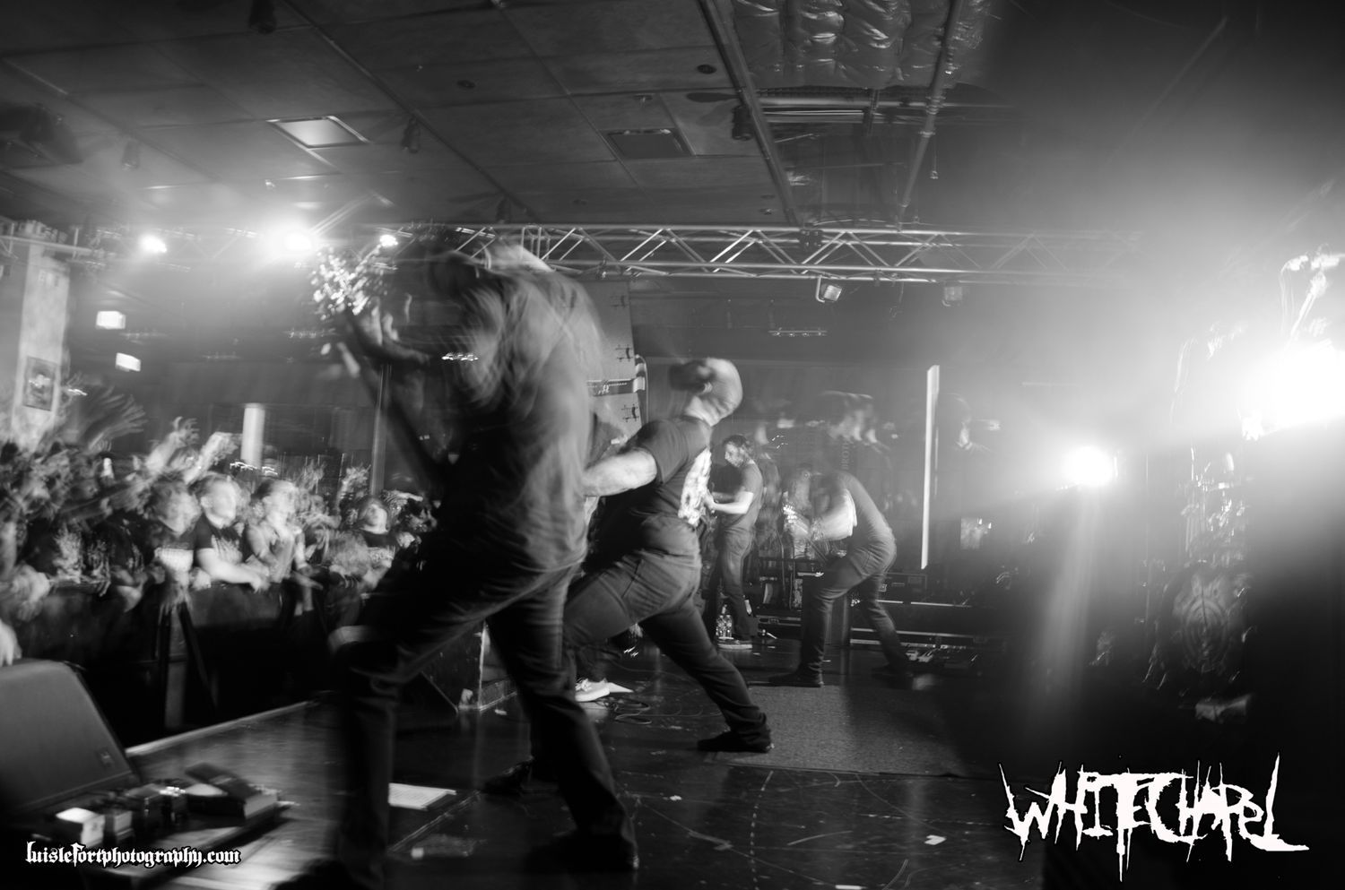 Energetic concert performance captured in black and white with crowd and stage lighting.