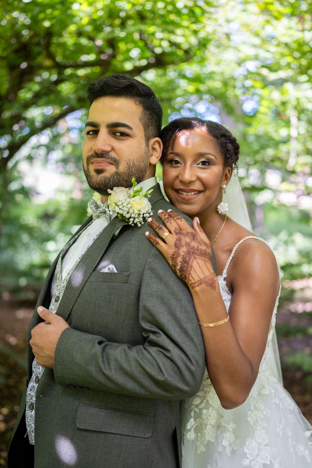 Un couple de mariés heureux pose en tenue de soirée sur un fond vert luxuriant.