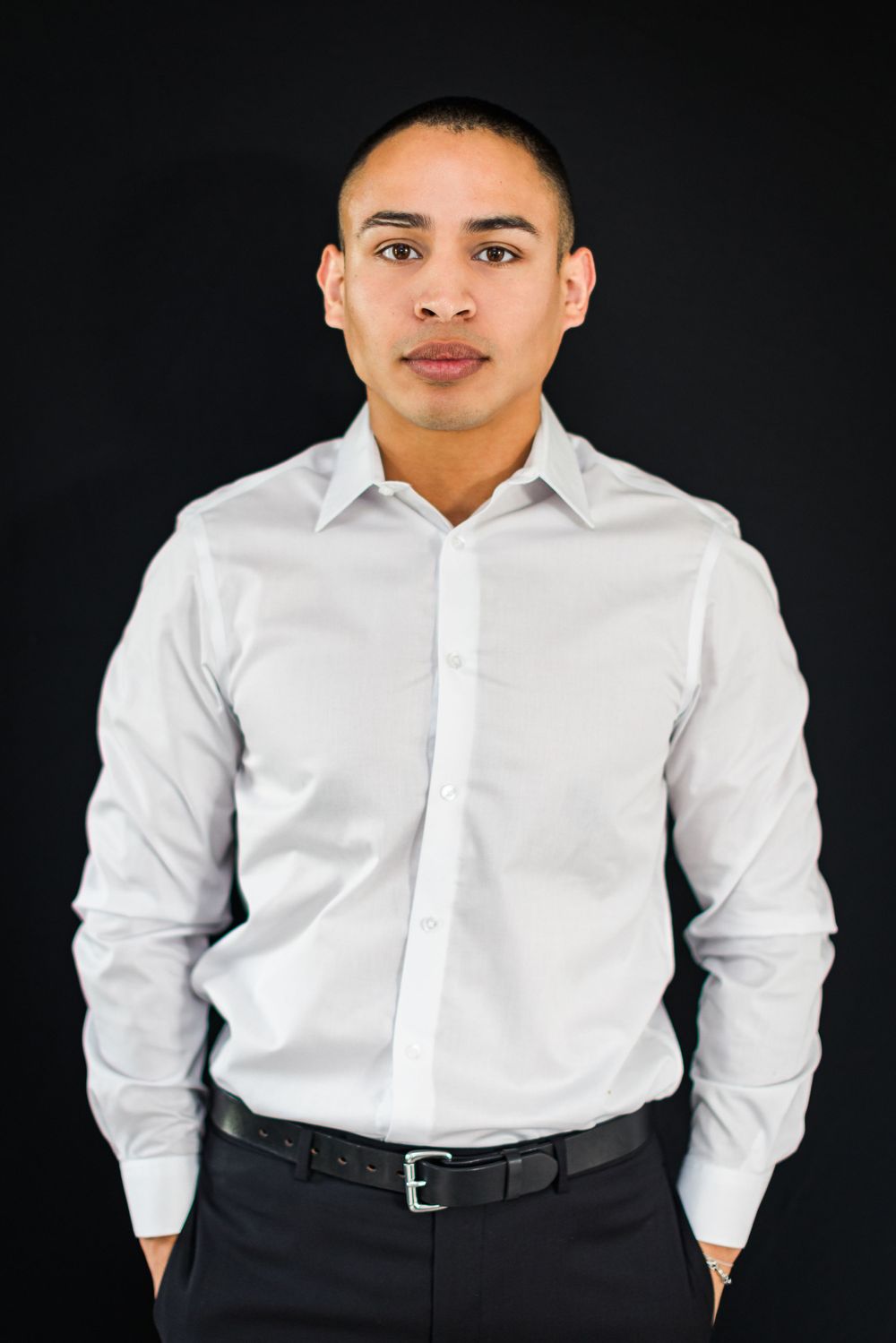Studio headshot of person in crisp white button-down shirt and dark pants.