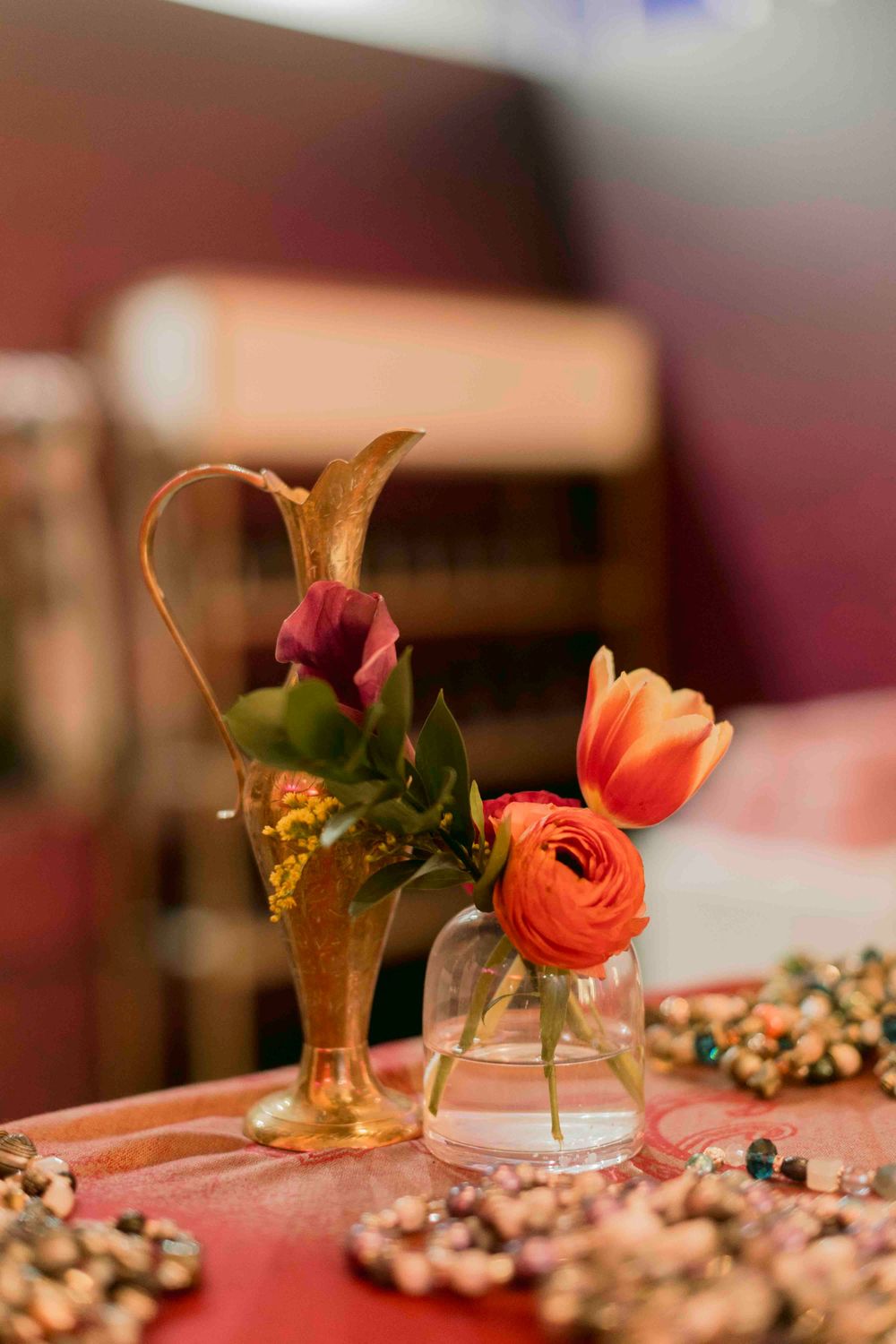 Gold vintage vase with dark calla lily and glass vase with orange tulip centerpiece.