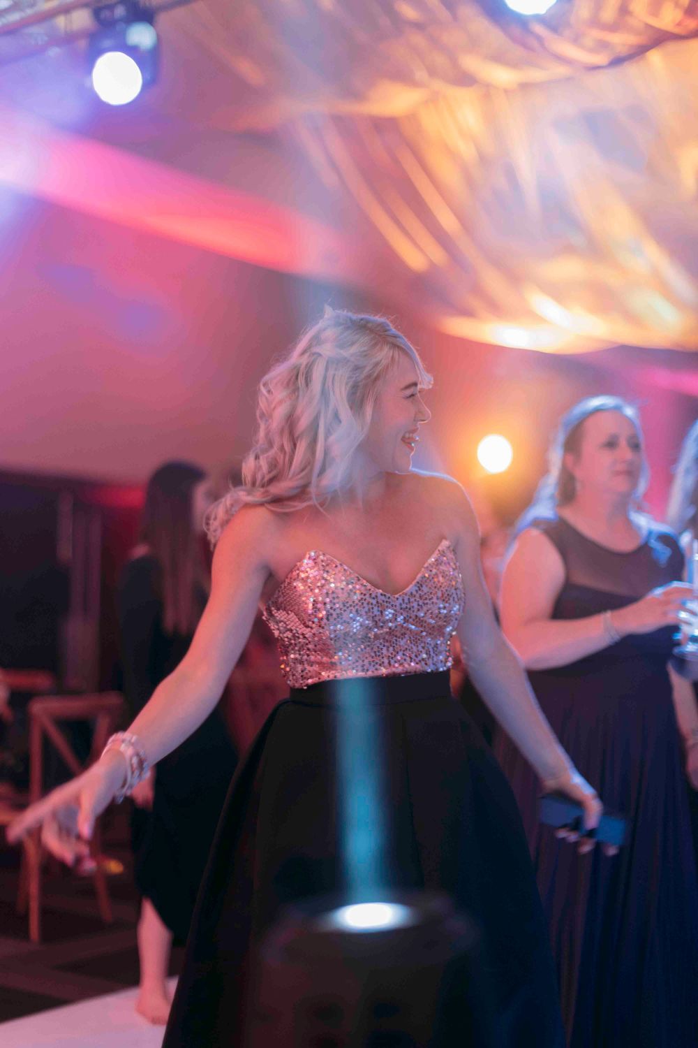 Woman in sequin top and black skirt dancing at a glamorous evening gala event.