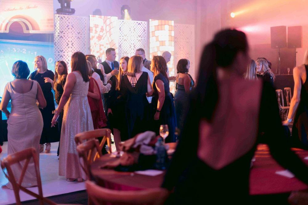 Guests mingling in formal attire at an upscale gala event with warm ambient lighting.