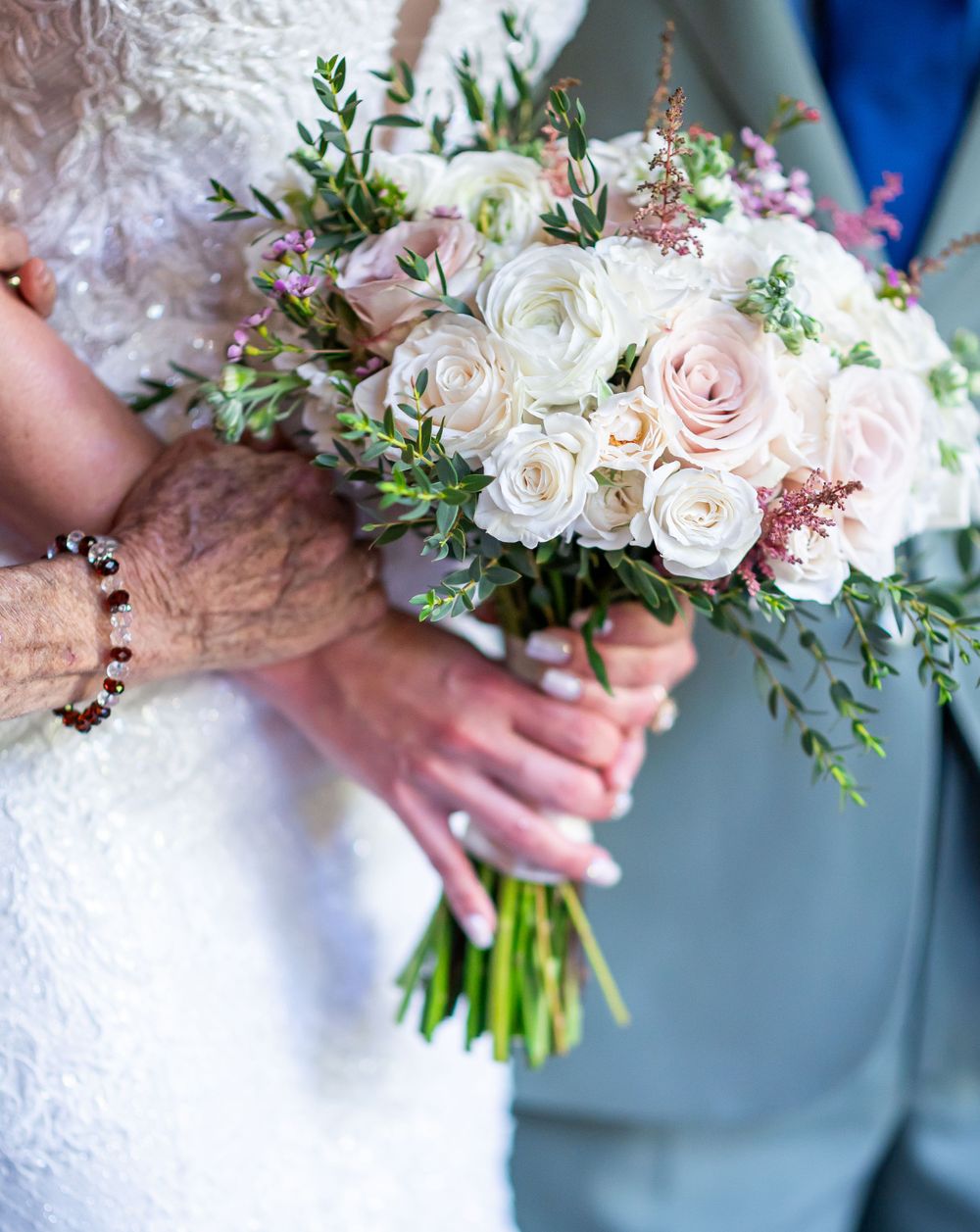 Delicate wedding bouquet featuring blush roses, white flowers and cascading greenery.