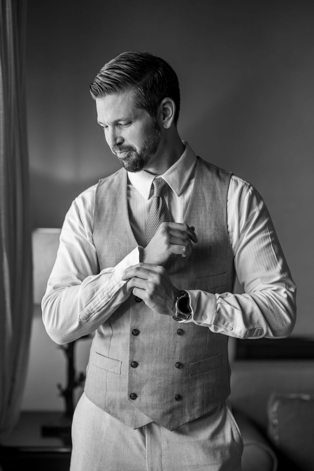 Classic black and white portrait of a person adjusting cufflinks.