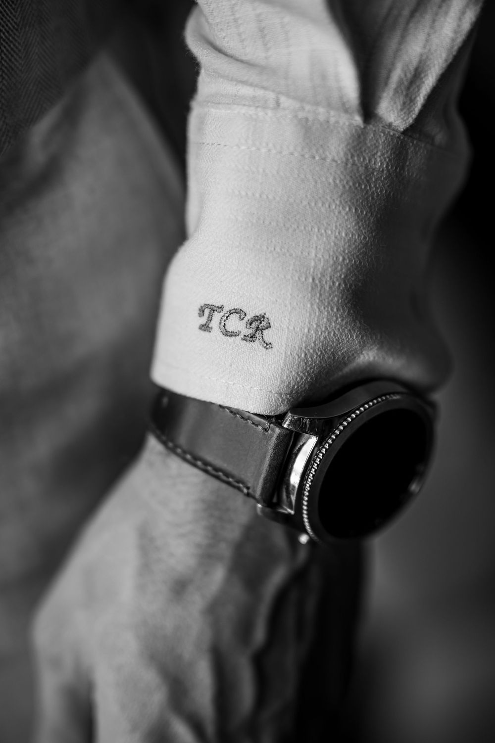 Close-up of a monogrammed shirt cuff with TCA initials and watch.