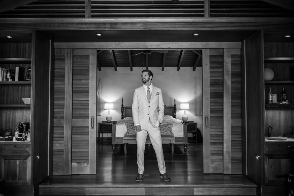 Black and white photo of a person in formal attire sitting in an elegant doorway.