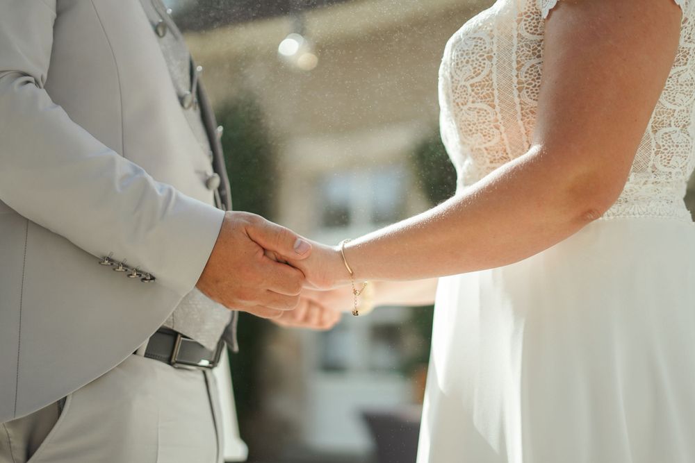 Close up of bride and groom holding hands during their wedding ceremony.
