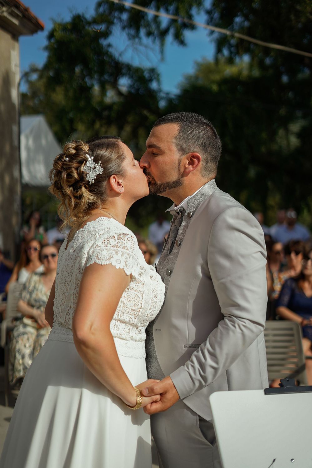 A newlywed couple shares their first kiss during an outdoor wedding ceremony.