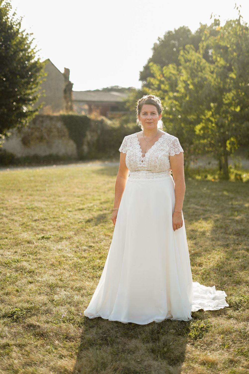 A wedding dress with delicate lace bodice and flowing skirt photographed in golden afternoon light.