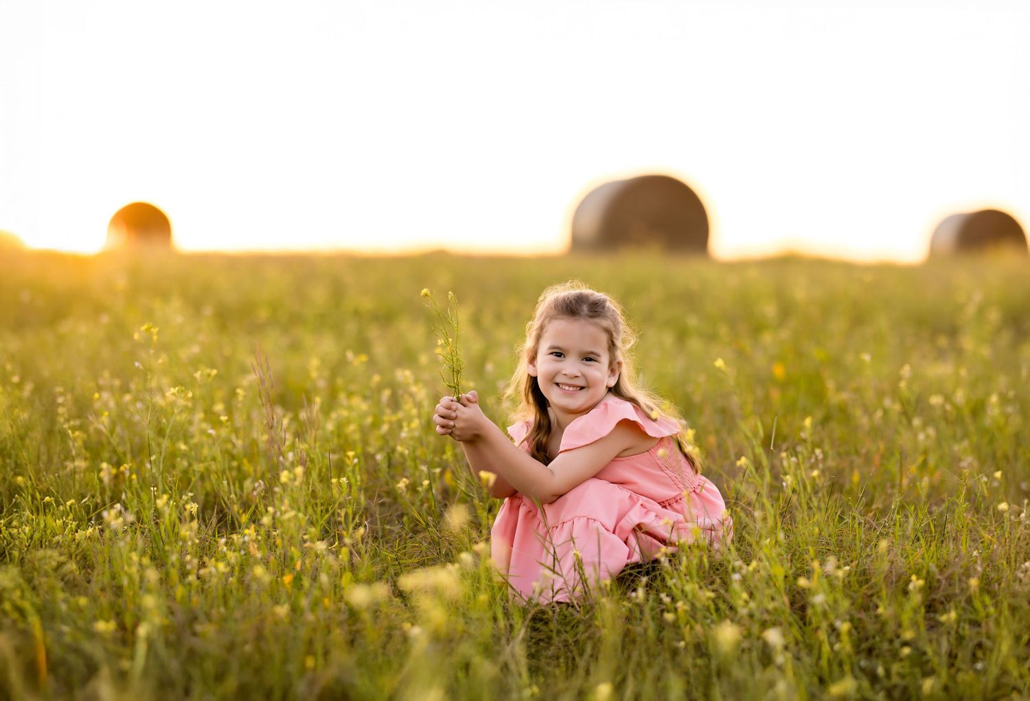 A joyful summer evening pose near hay bales in a wildflower meadow. Photos by Tampa Photographer DigitalMyst Photography