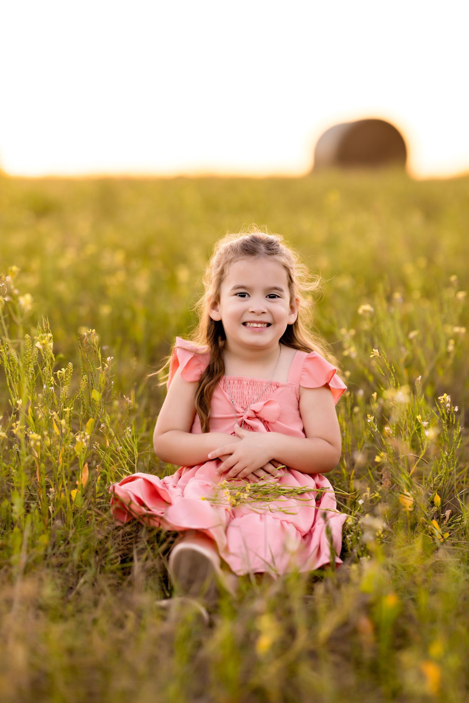 A cheerful moment captured in a pink dress among wildflowers at sunset.