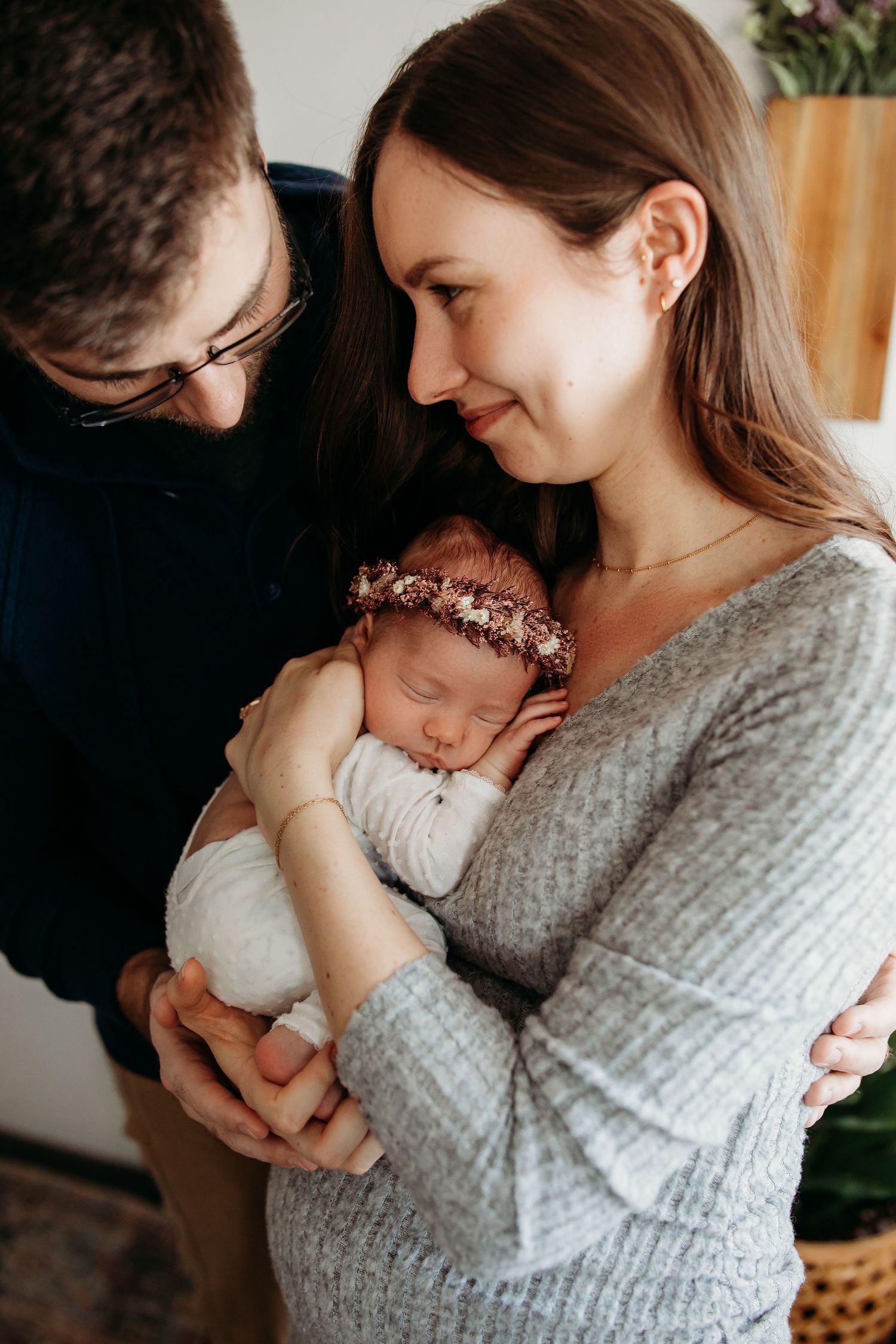 Intimate at-home lifestyle photo session with newborn baby swaddled in white.