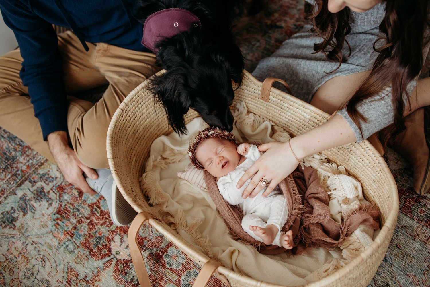 Family cuddles with newborn baby on floor during intimate lifestyle photo session.