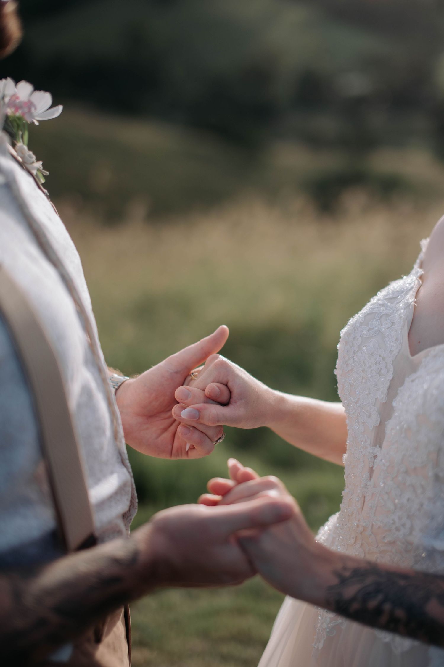 Close-up of couple's hands exchanging rings during outdoor wedding ceremony.