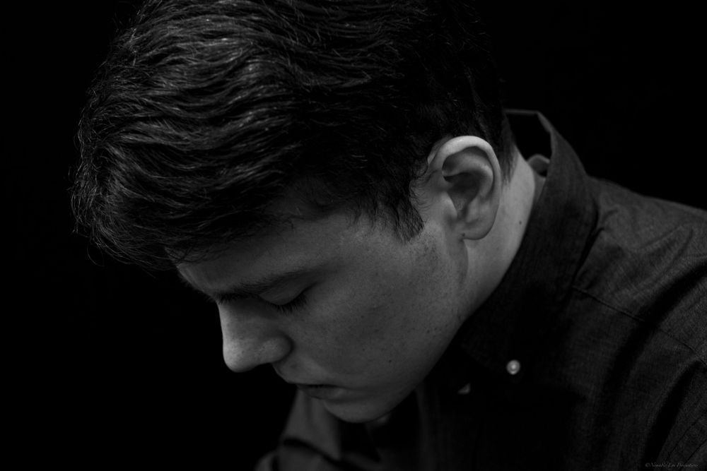 Moody black and white profile shot of a figure in dark clothing.