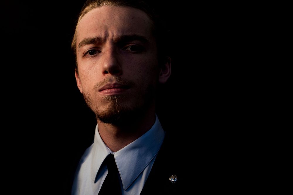 Cinematic side-lit portrait of person in business attire against black backdrop.