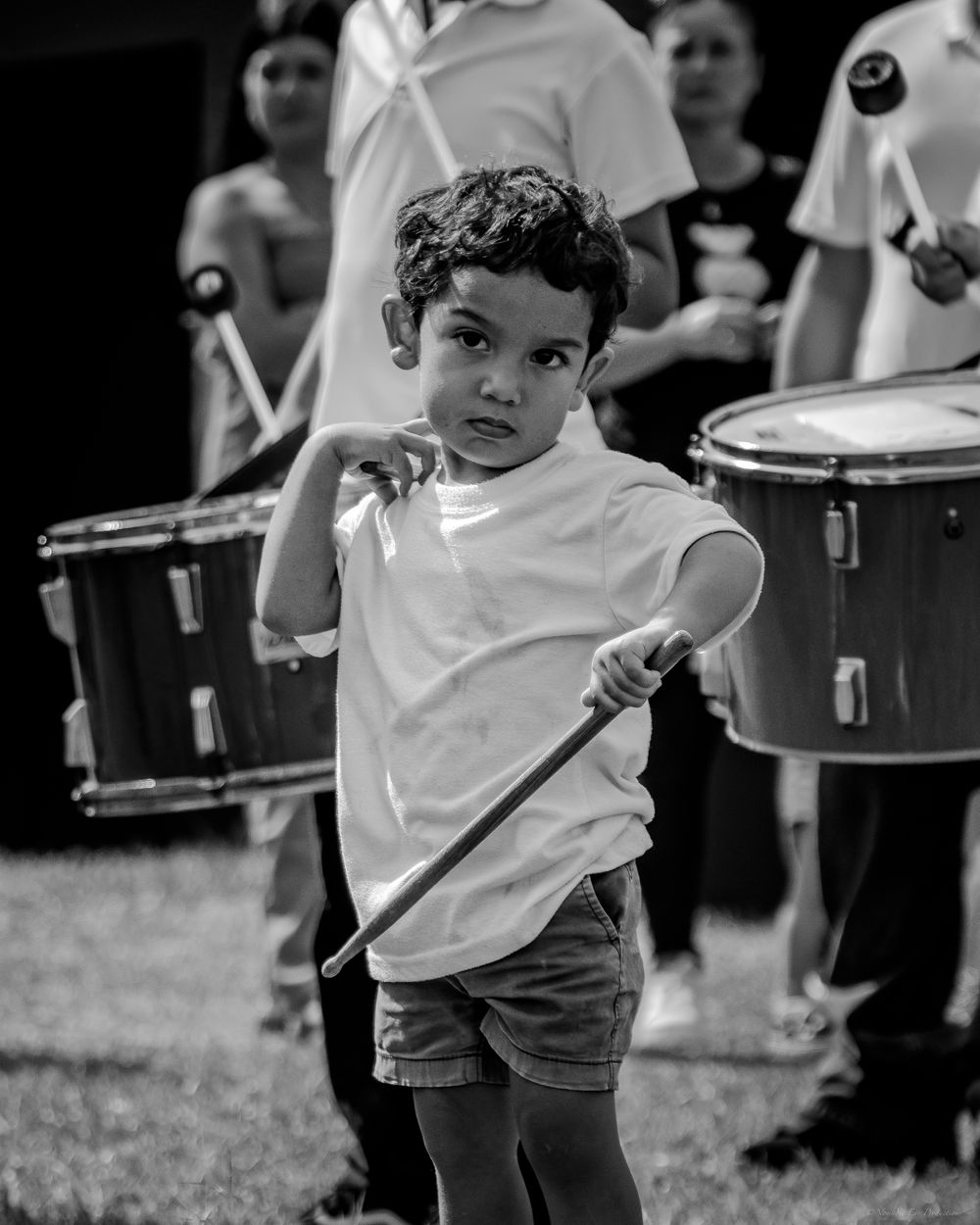 Black and white portrait of young drummer holding mallets during outdoor performance.