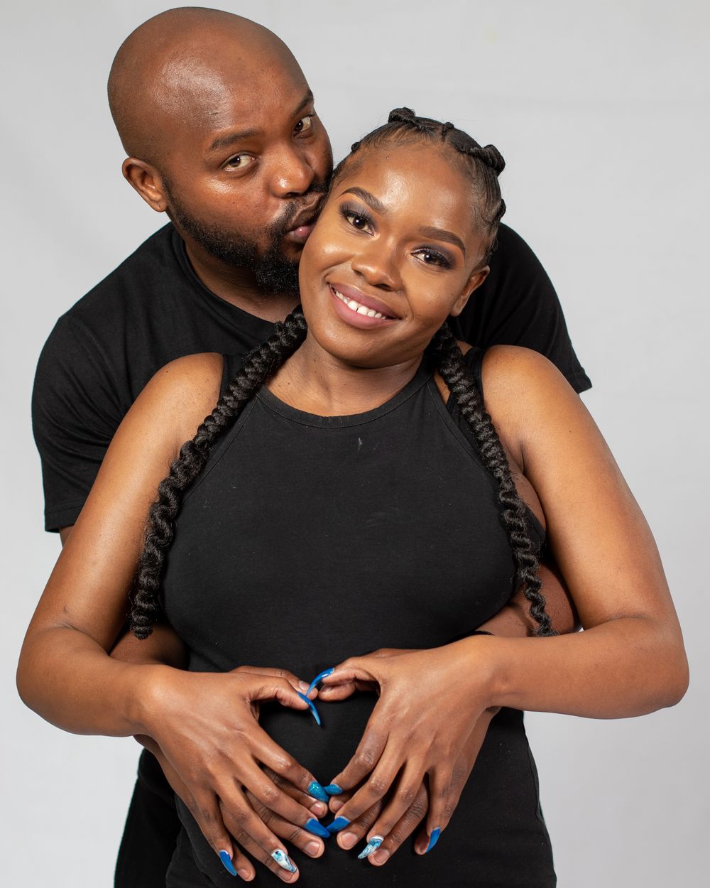 A couple in black clothes poses together for a romantic maternity photo.