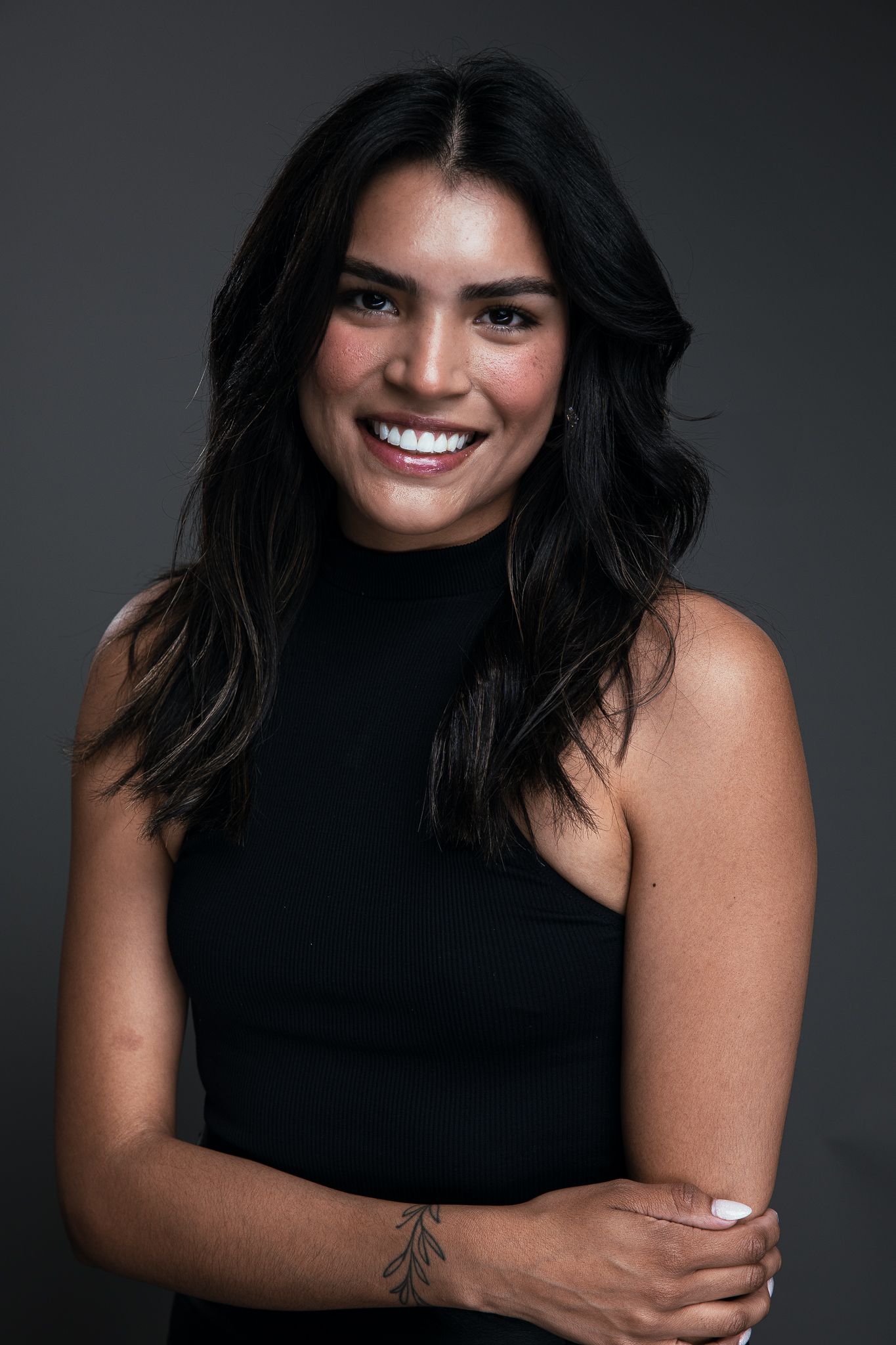 Professional headshot against soft lighting wearing black blazer and white shirt.