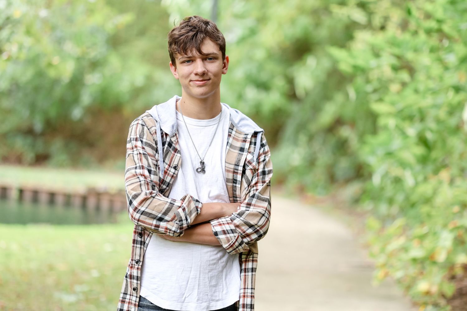 A casual portrait of someone wearing a plaid button-up shirt over a white t-shirt in a garden setting.