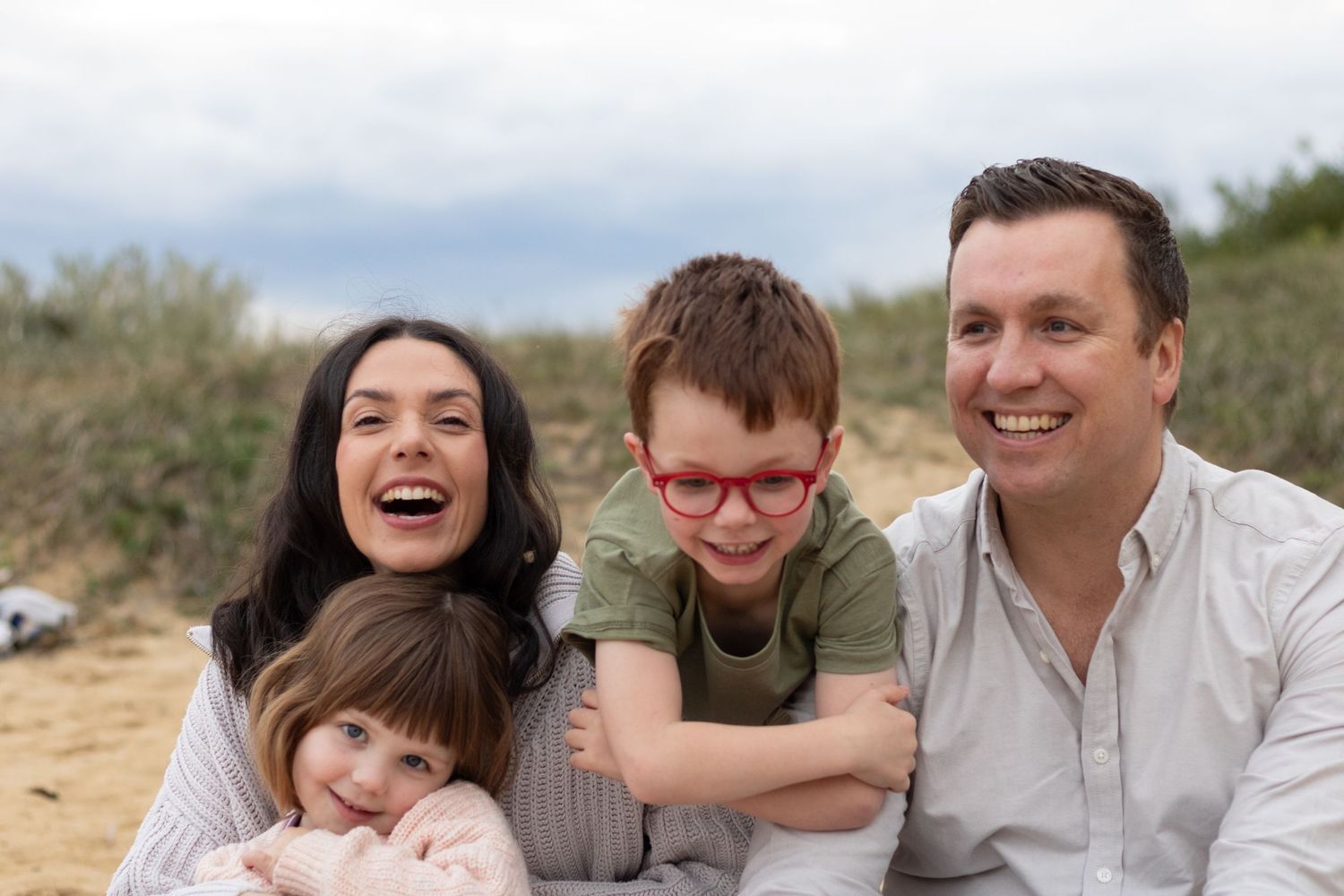 Happy family enjoying time together outdoors on a sunny day on grassy hillside.