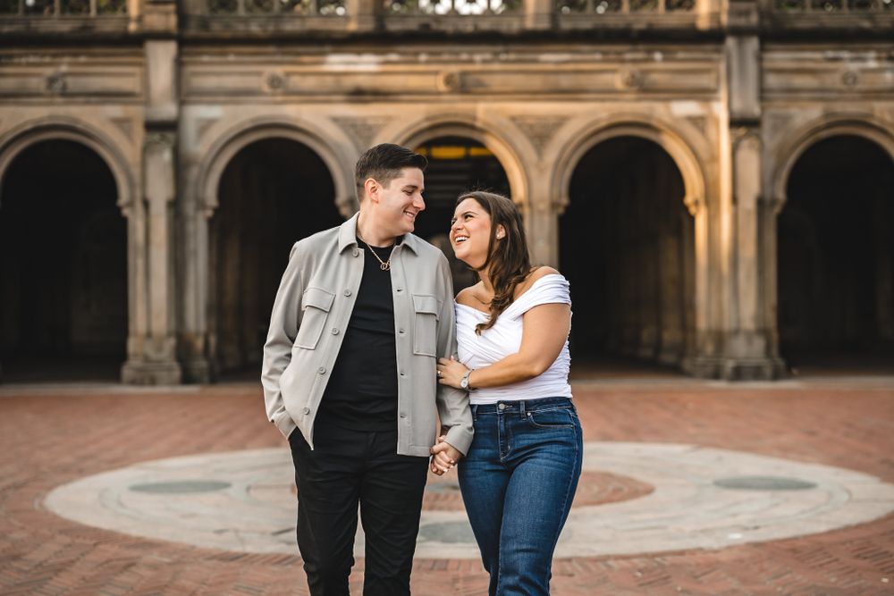Couple posing in front of ornate stone archways and architectural details.