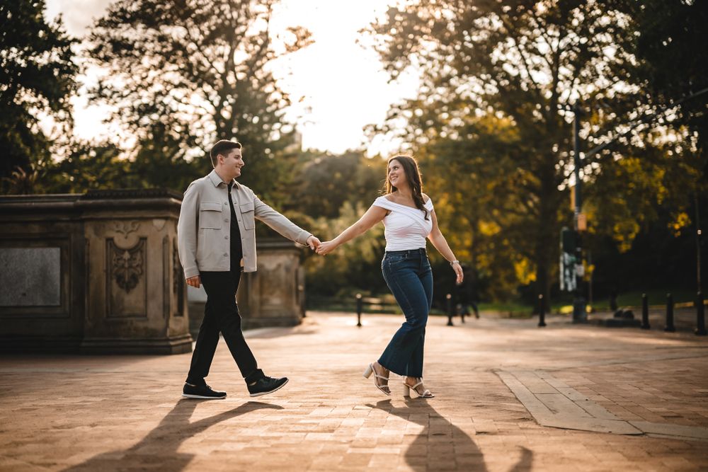 A couple poses playfully on historic stone steps during a sunset photoshoot.
