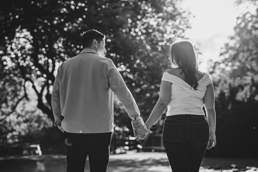 Black and white photo of a couple walking together in a park setting.
