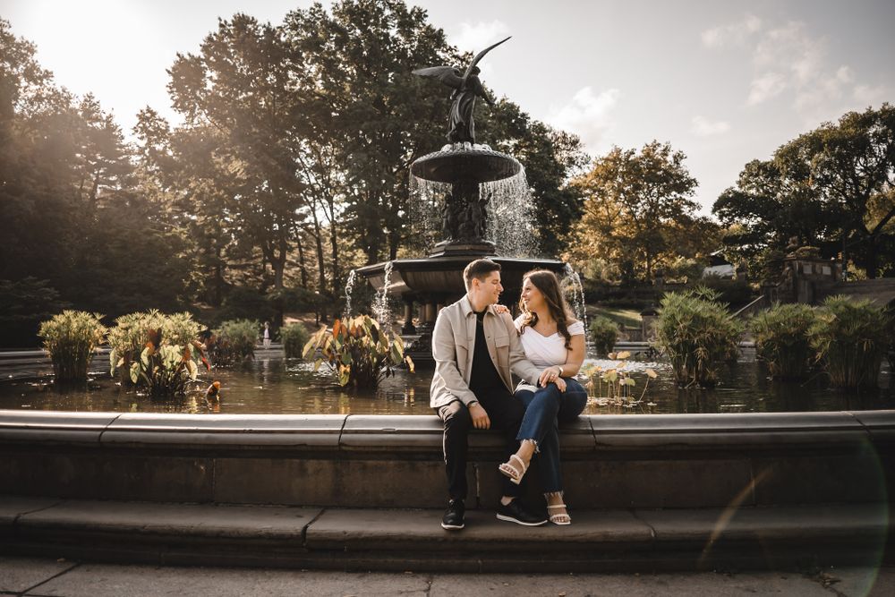 Couple sits on stone railing during sunset in an urban park.