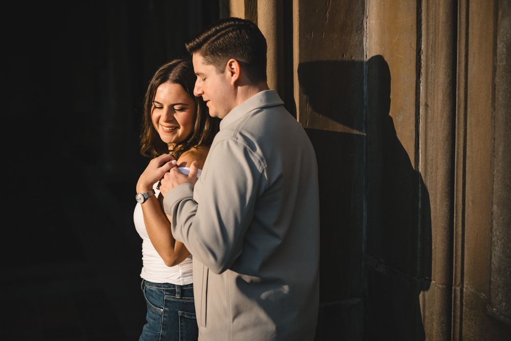 Couple sharing intimate moment under historic stone archways.