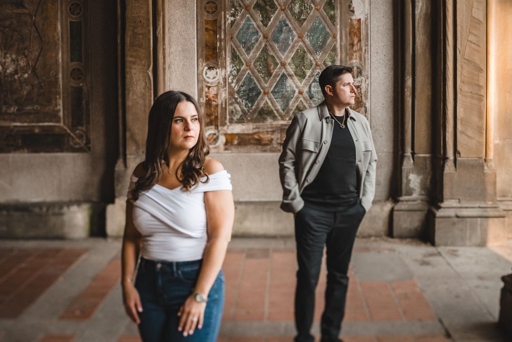Couple posing in elegant stone corridor with decorative wall panels.