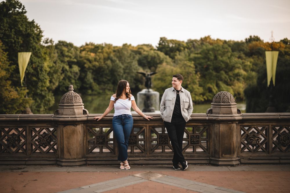 A romantic couple stands on ornate stone steps in a park during golden hour.