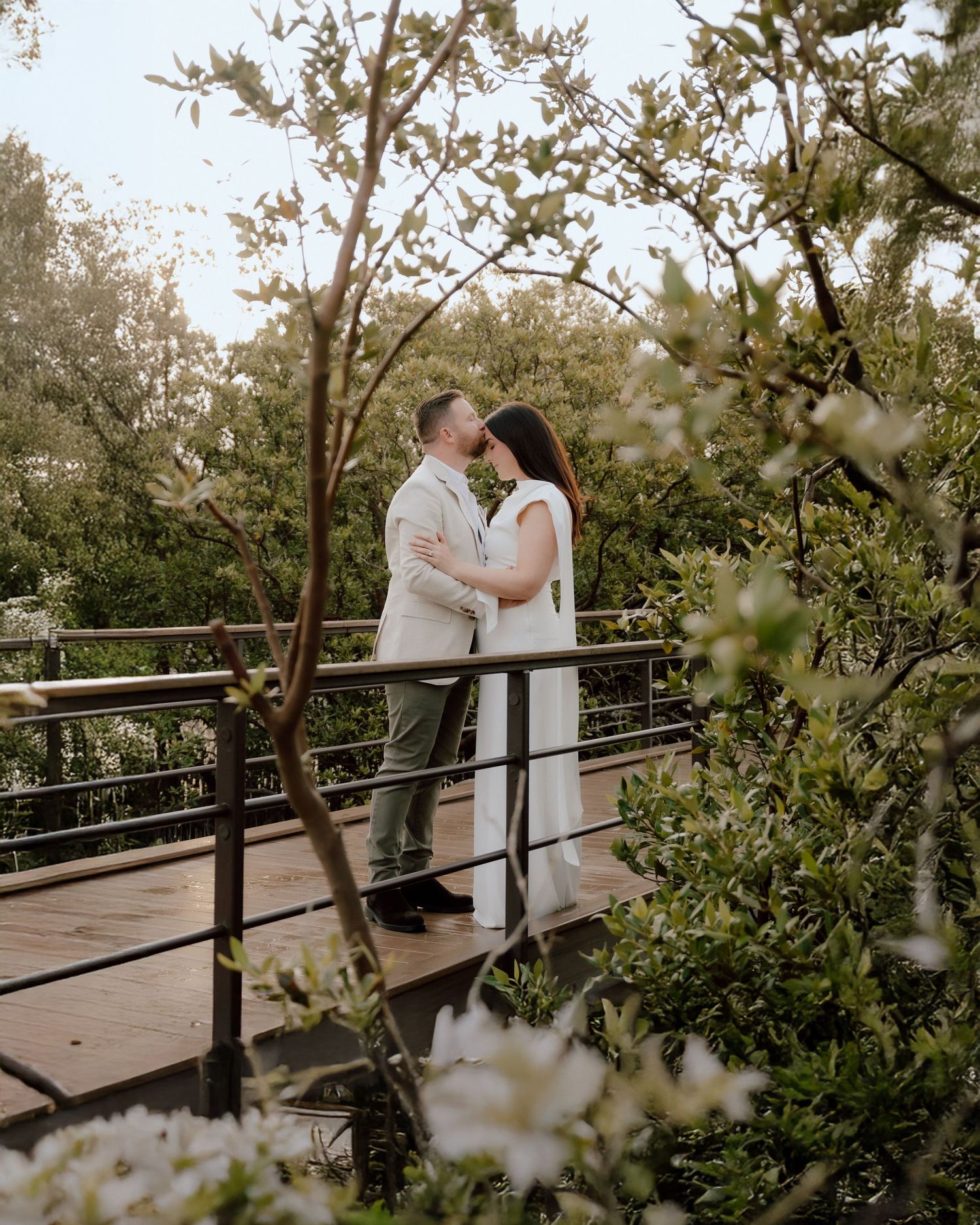 Romantic couple embracing on wooden bridge during outdoor wedding photoshoot