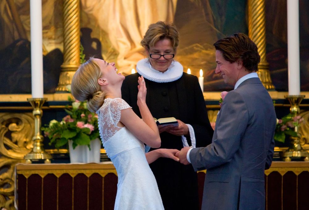 A wedding ceremony takes place in an ornate church with golden decorations and candlelight.