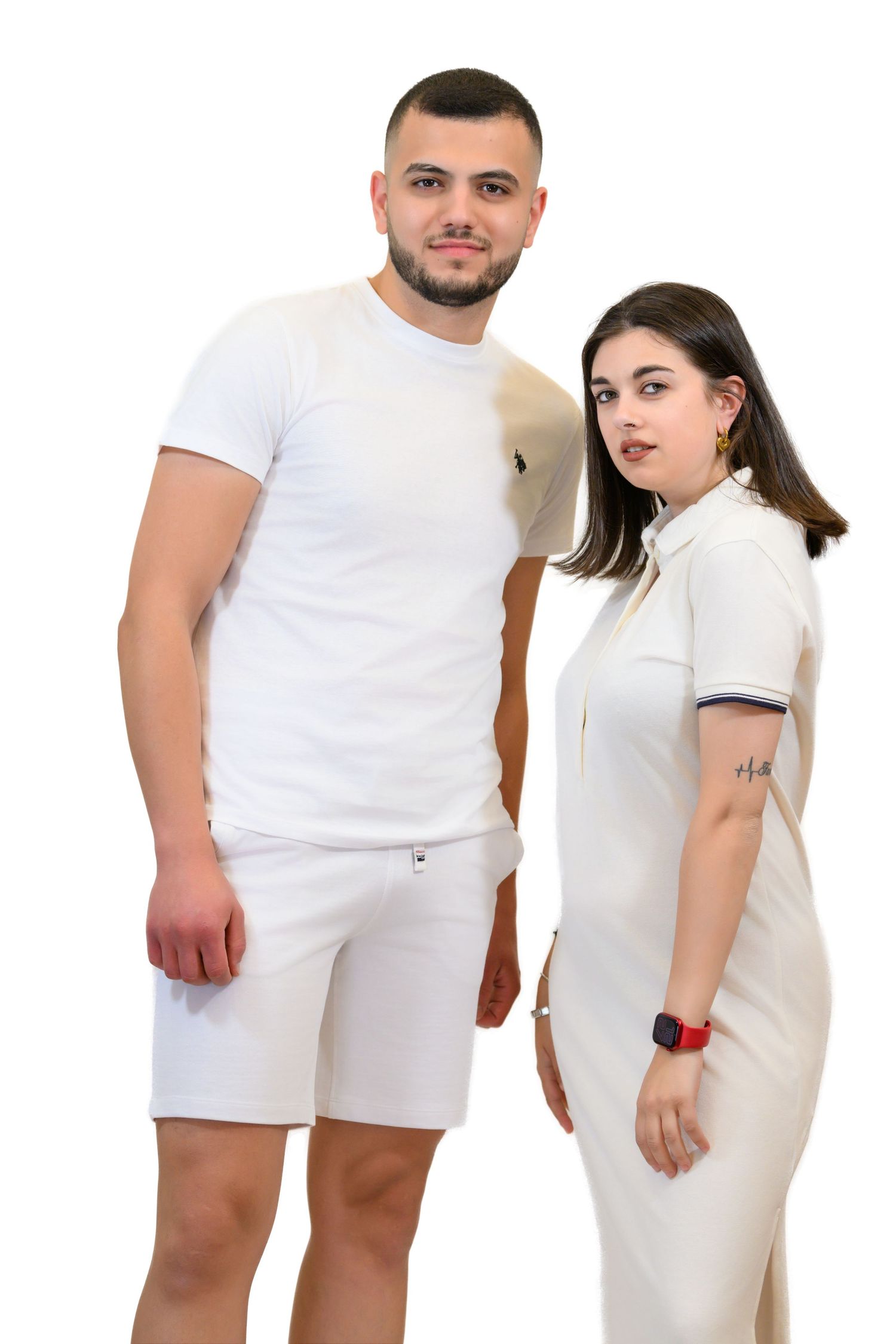 A couple in all-white outfits posing against a plain background for a portrait.