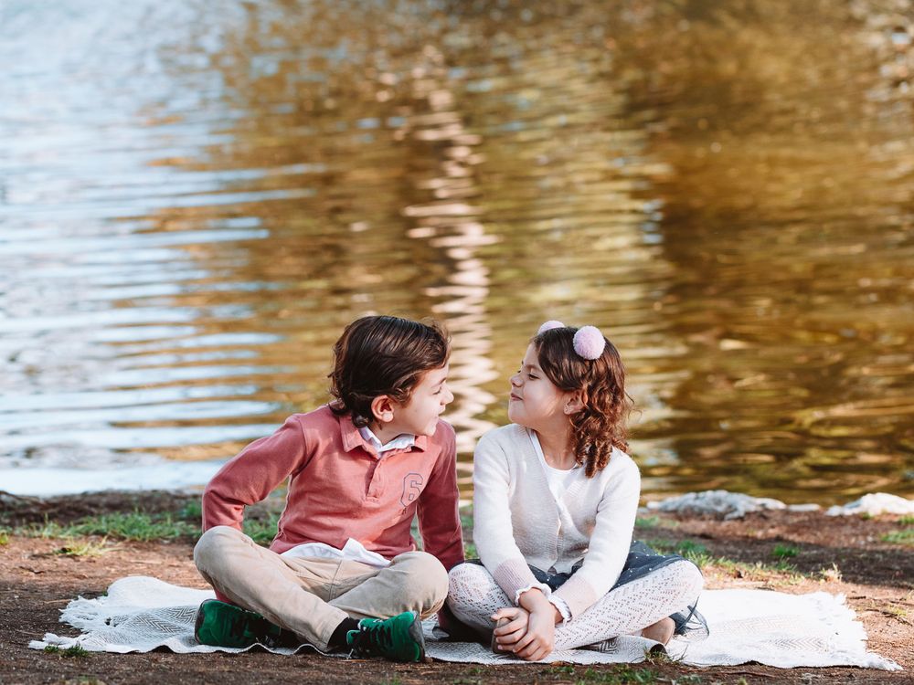 Romantic couple photoshoot by a golden reflective lake at sunset.